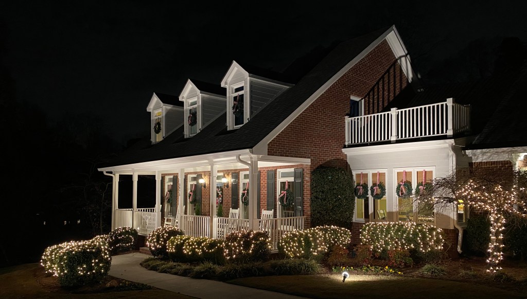 Exterior of house decorated with lights and wreaths for Christmas.