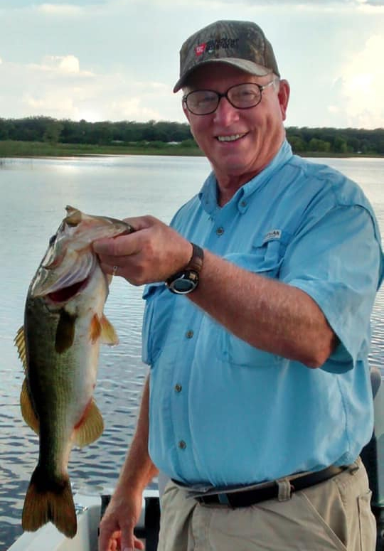 Larry Wallace holds a largemouth bass in a boat on a lake in Central Florida