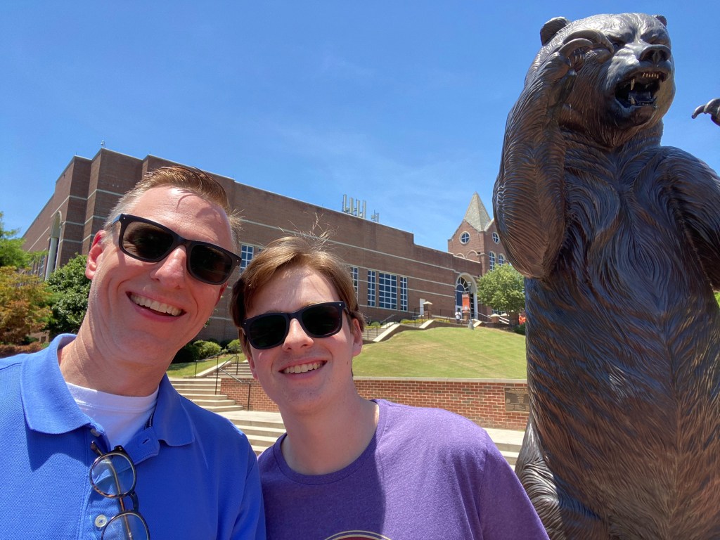 Lance and Harris pose with the bronze statue of the Mercer Bear in front of the University Center building.