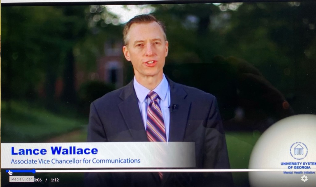 Lance Wallace wearing a suit and tie talks on a video about mental health for the University System of Georgia.