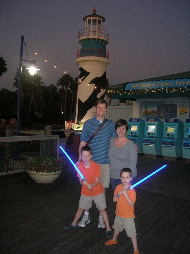 Lance and Carla Wallace stand with their two young sons holding blue light sabres in front of a lighthouse at the gate to Sea World in Orlando, Florida.