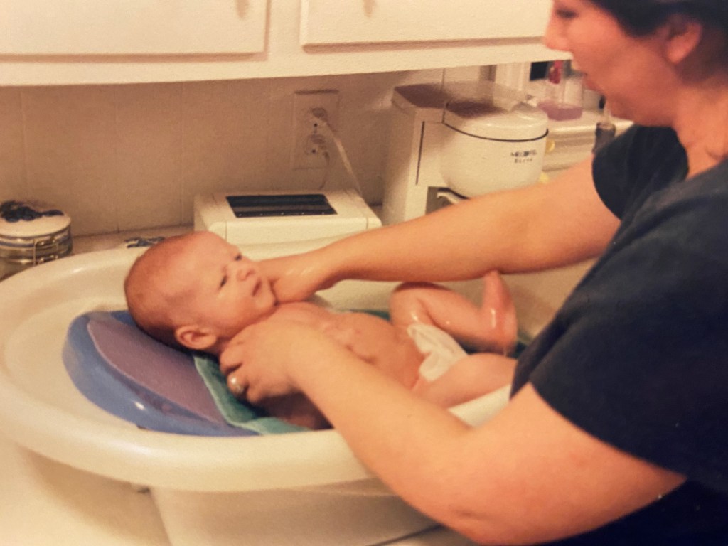 Carla Wallace gives infant Barron Wallace a bath in a plastic baby tub on the kitchen counter.