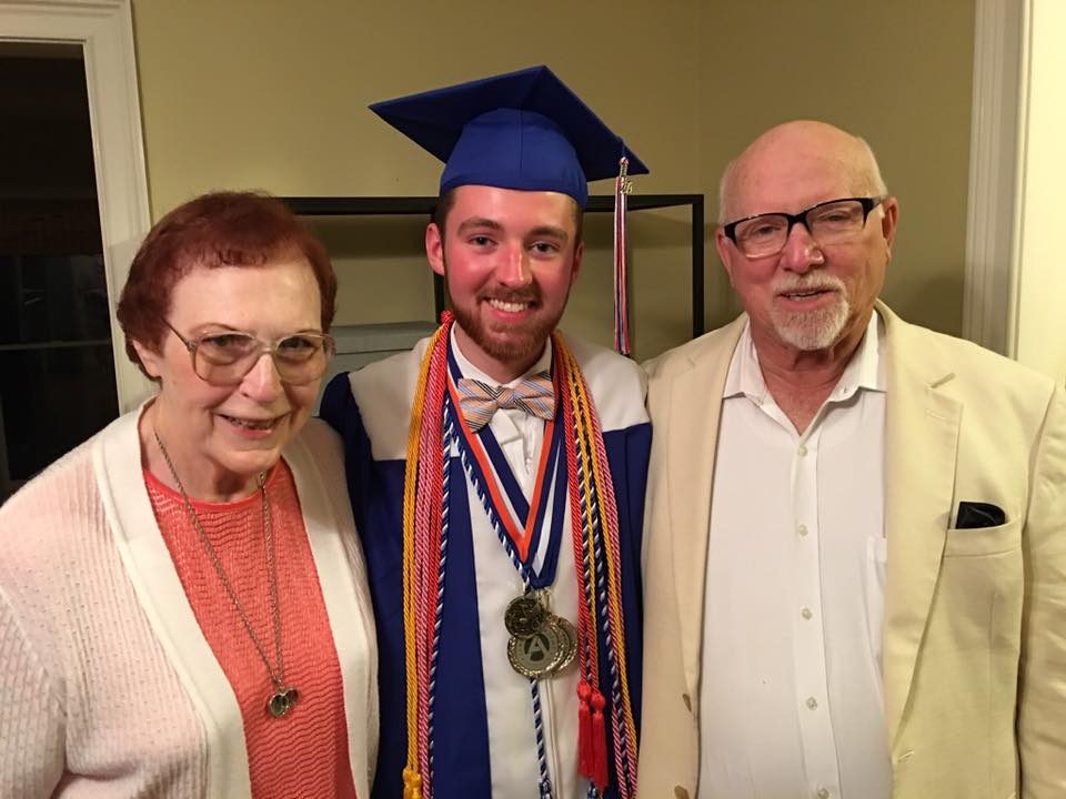Sharon and Larry Wallace stand with Barron Wallace, dressed in his blue high school graduation regalia, in the middle.