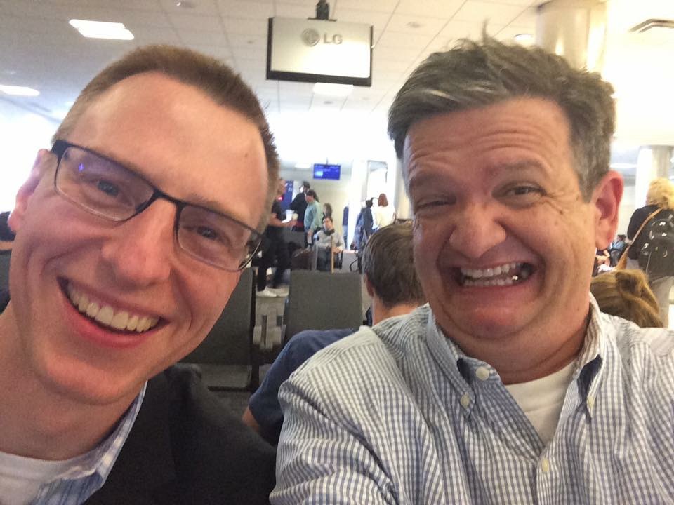 Bob Perkins and Lance Wallace make silly grins for a "selfie" in a waiting area at the Atlanta Airport.