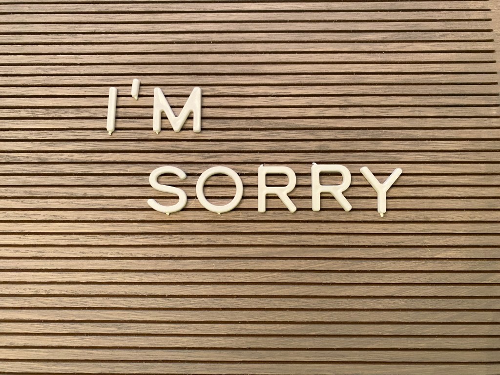 I'm Sorry in white lettering on a gray wooden background