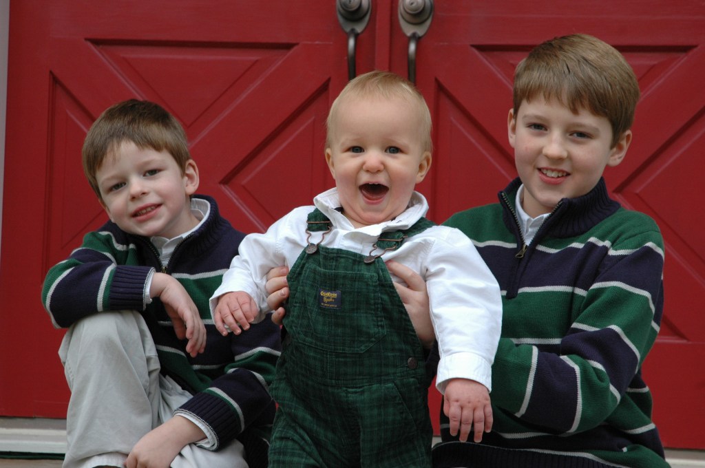 Harris, Carlton and Barron Wallace sitting in front of red front doors as children.