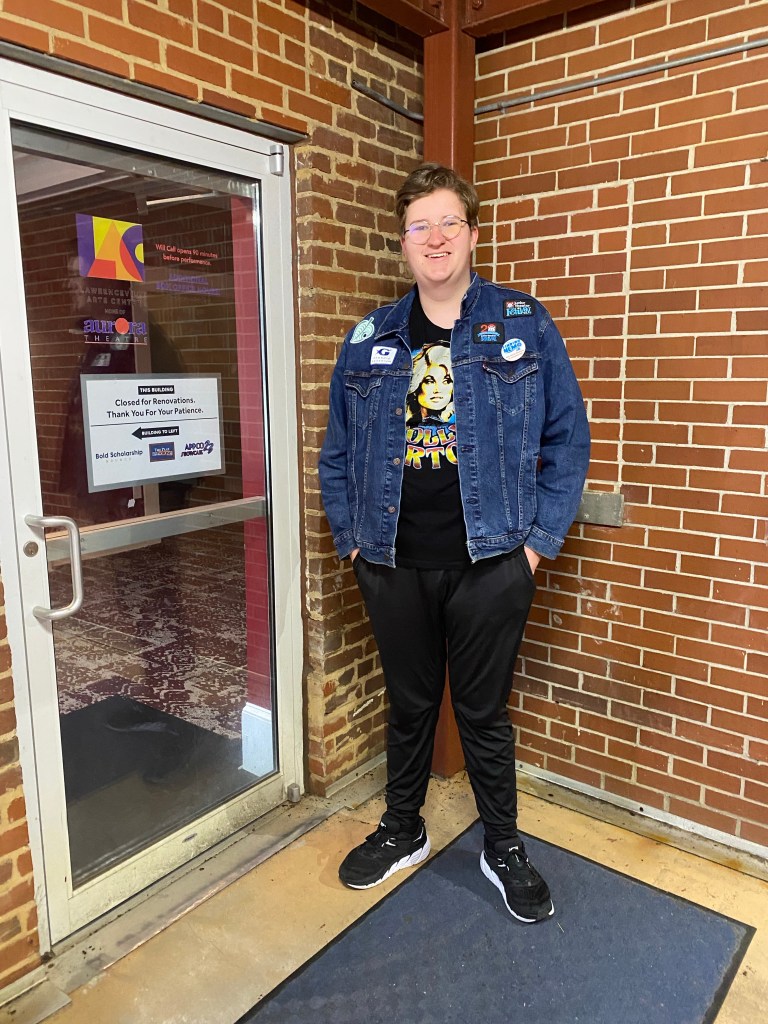 Carlton Wallace in a denim jacket and black t-shirt stands at the employee entrance of the Aurora Theatre in Lawrenceville, Georgia.