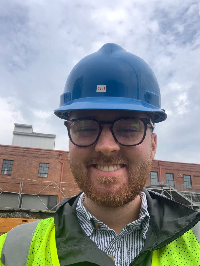 Barron Wallace in a blue hard hat and reflective yellow vest on a construction site at the University of Georgia.