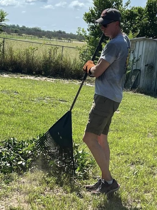Lance Wallace raking up clippings from a shrub