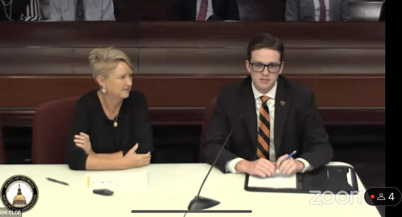 Woman and college student sit at a table with a microphone