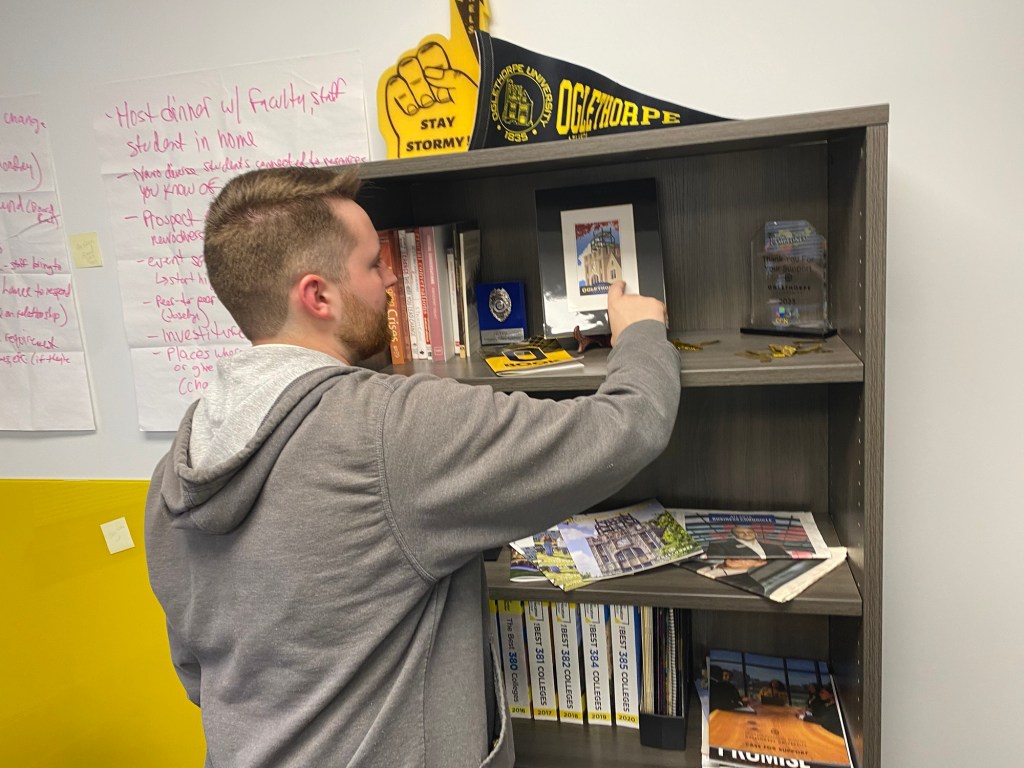 a young man looks at items on a bookcase