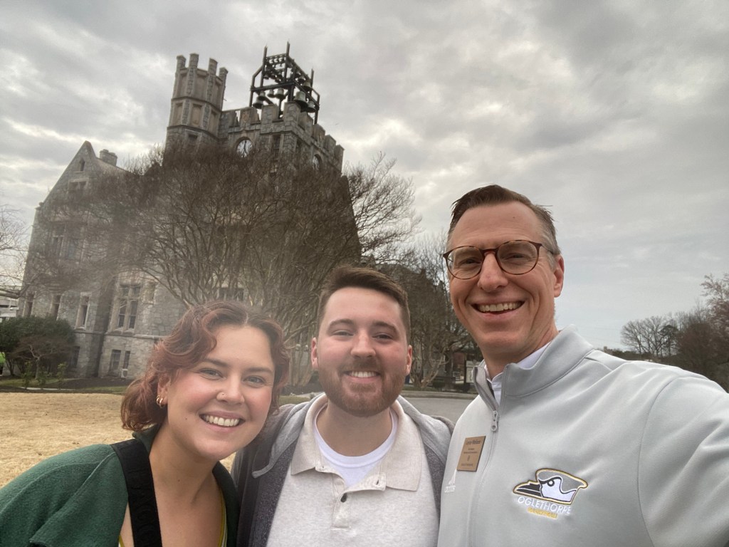 three people in front of historic stone building