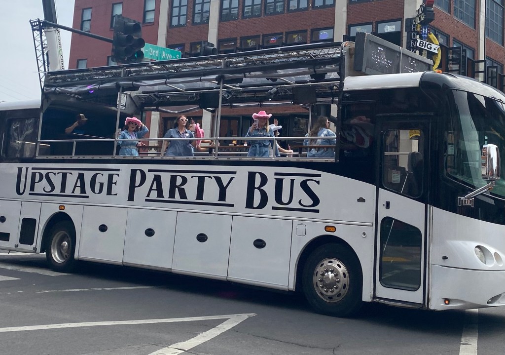 girls in pink cowboy hats drinking on an open-air bus