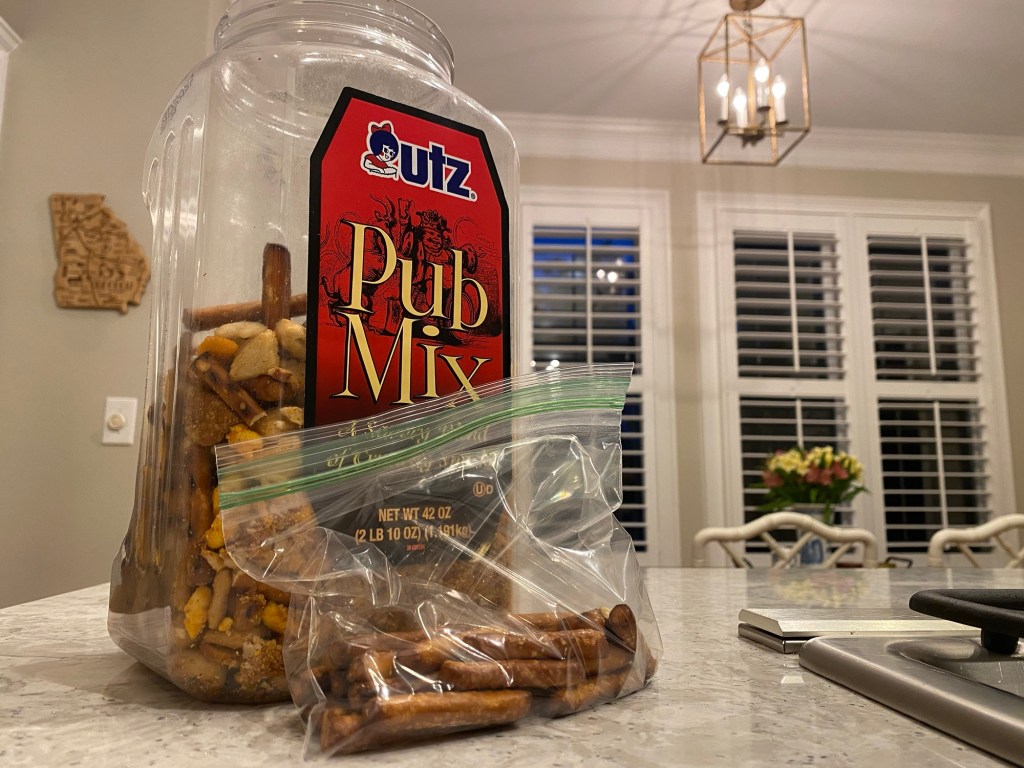 Utz Pub Mix container and a plastic bag of pretzels on a kitchen counter