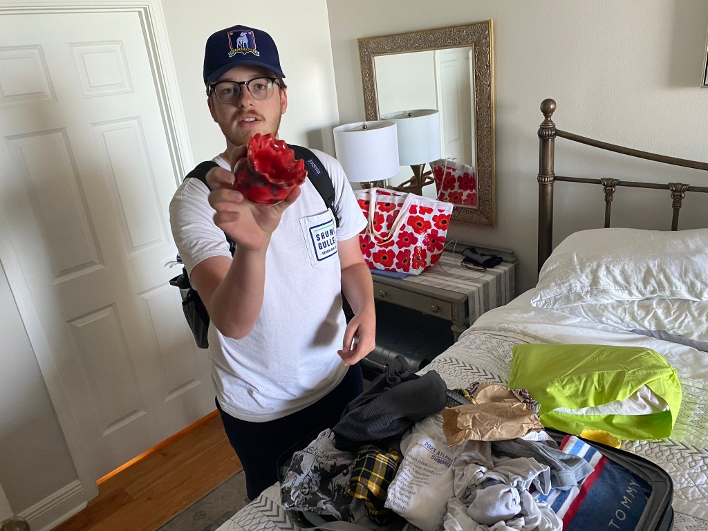 young man holding a small, red handmade pottery bowl