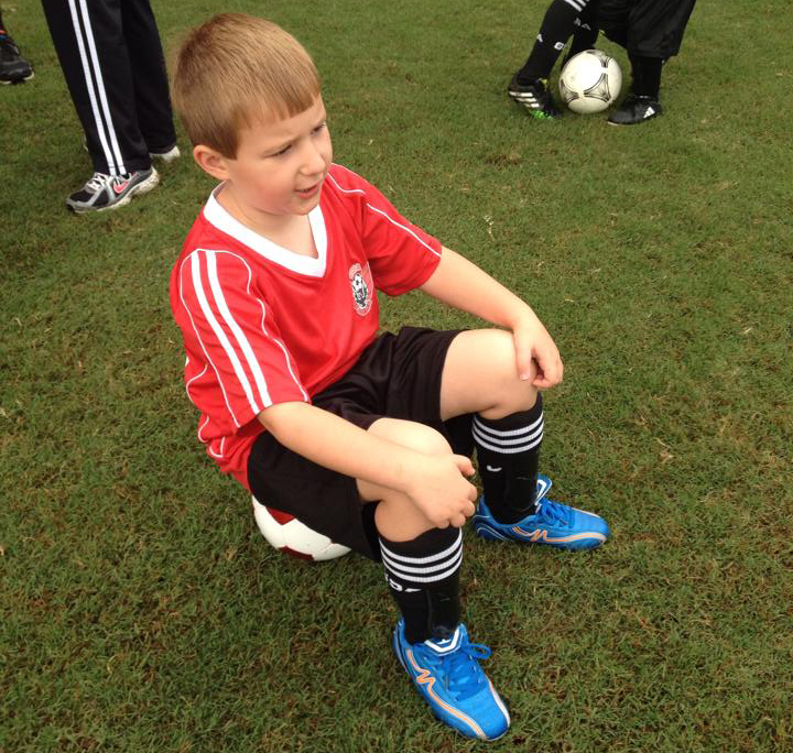 boy sitting on a soccer ball