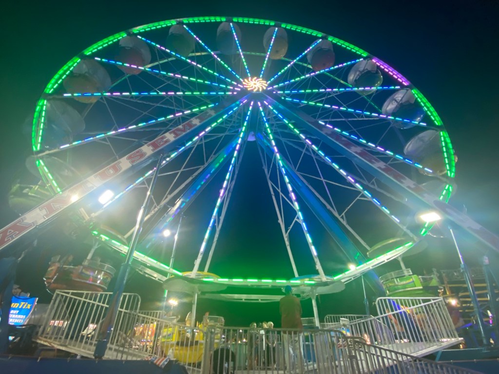 a ferris wheel illuminated green at night