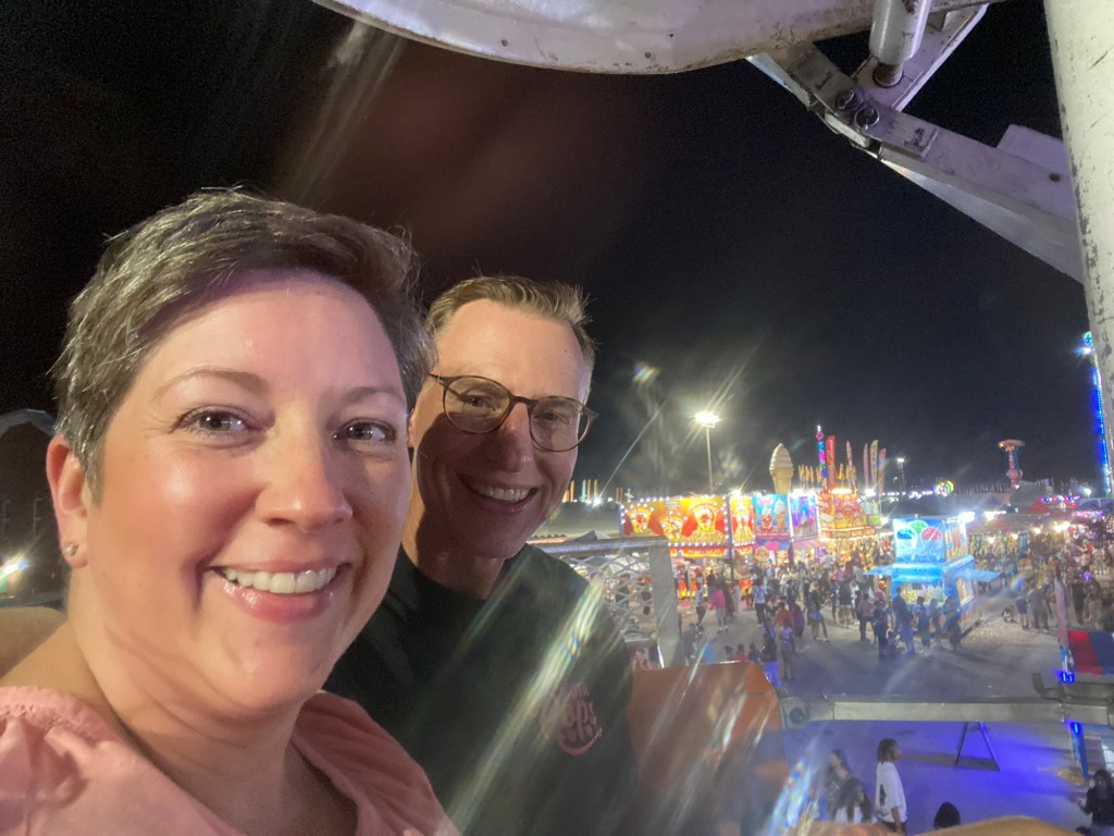 A woman and man in a ferris wheel gondola overlooking the fairground