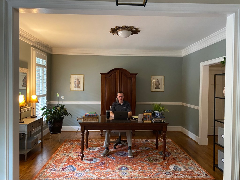 A man on a laptop at a desk in a home office
