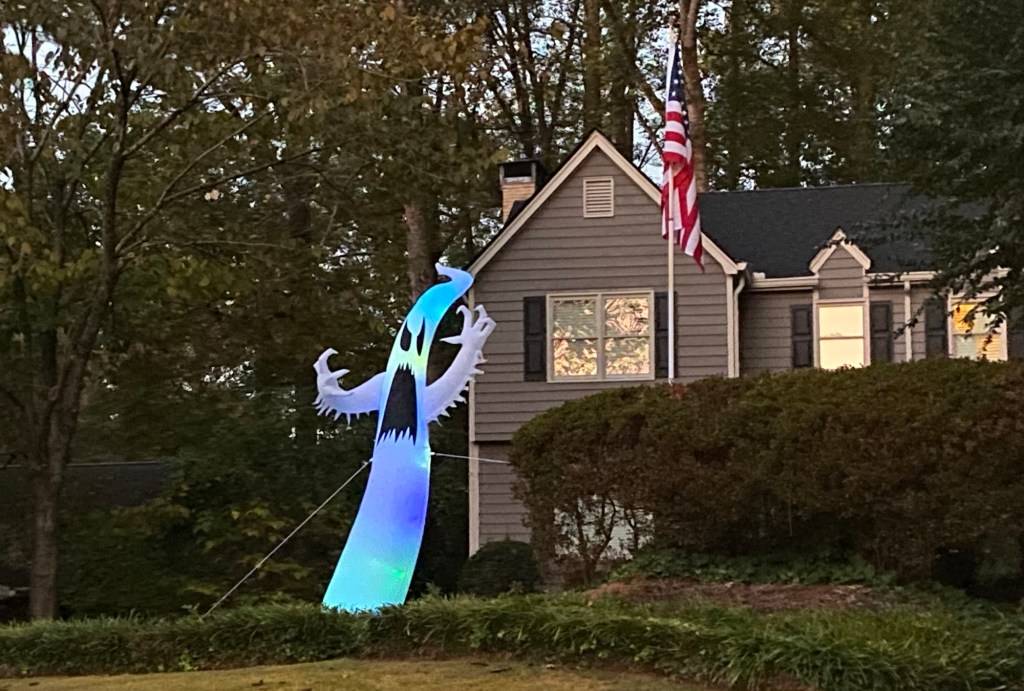 inflatable ghost next to an American flag on pole