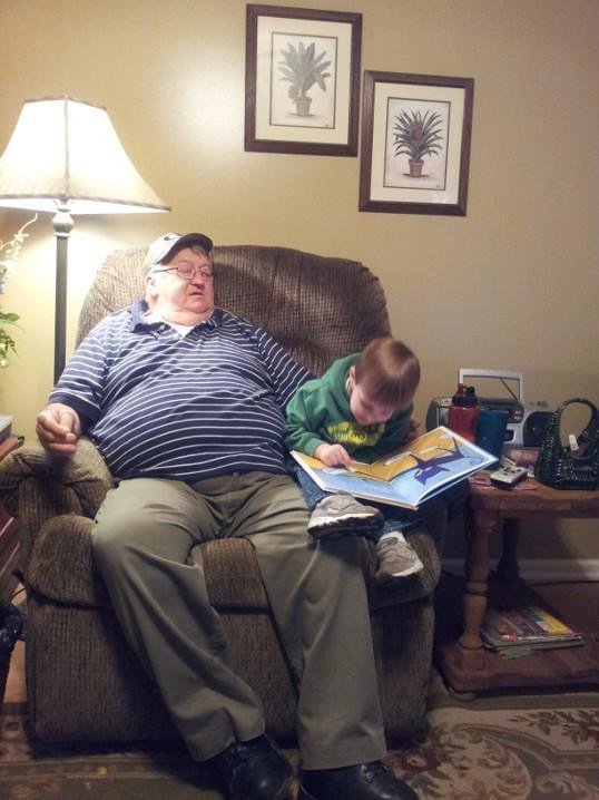A child reads a book to his grandfather