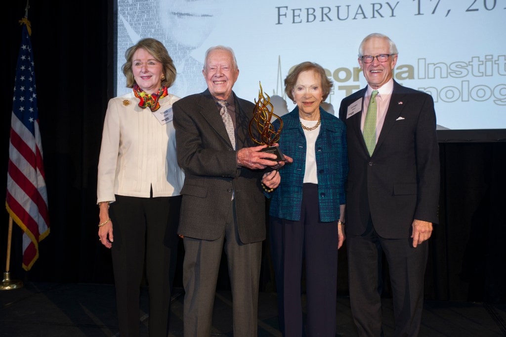 President Carter stands with Rosalynn Carter and two others holding an award