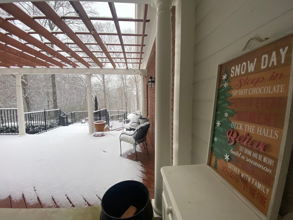 snow day decorative sign on a back porch covered in snow