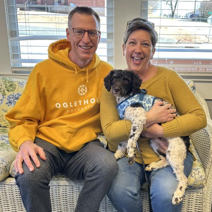 A man and woman with a brown and white miniature poodle
