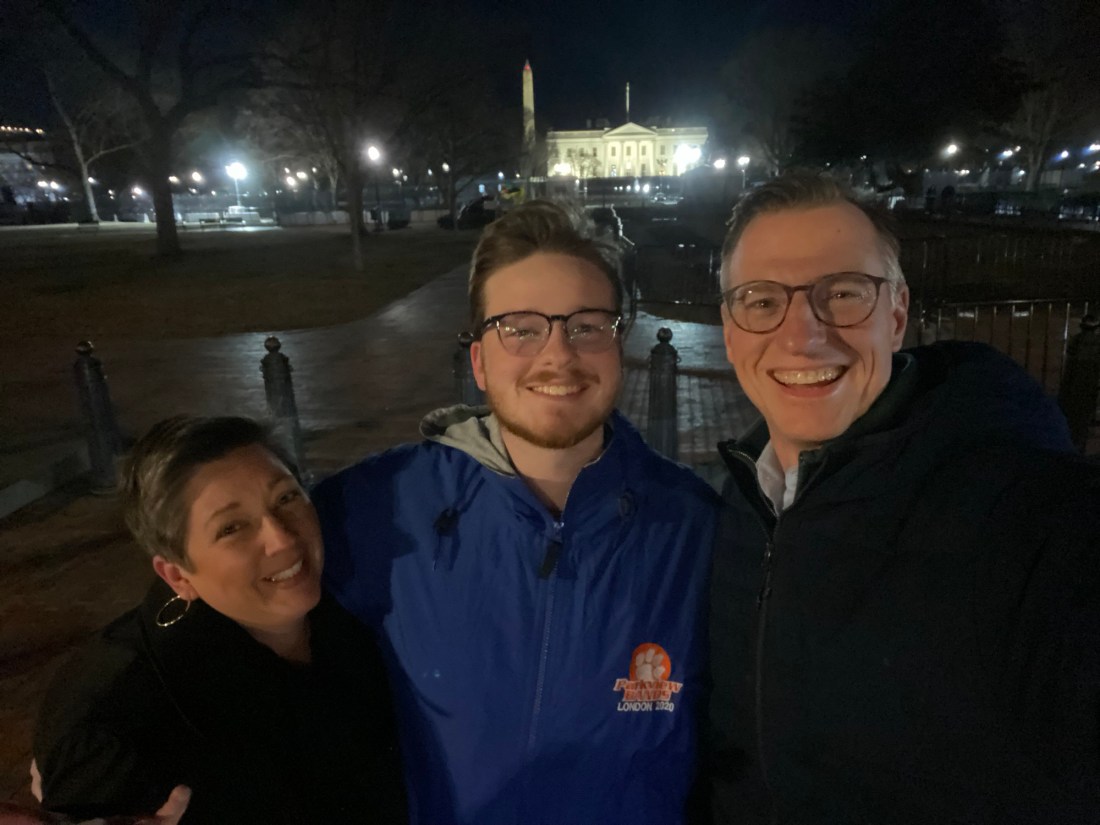 Two men and a woman outside the back gate of the White House