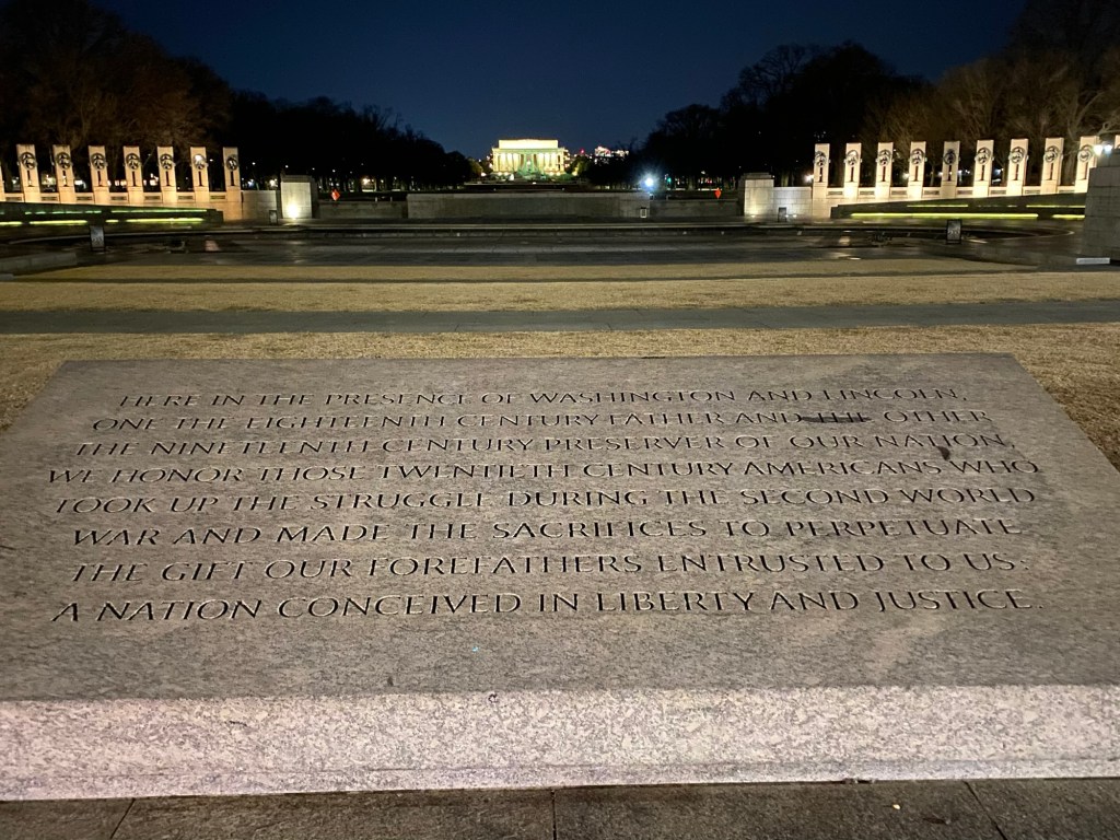 World War II memorial at night in the foreground with the Lincoln Memorial in the background