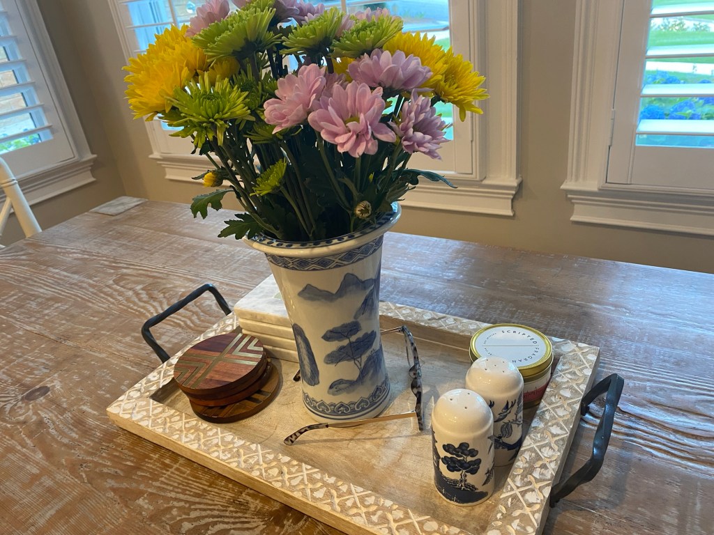 Kitchen table with flower arrangement, drink coasters and reading glasses