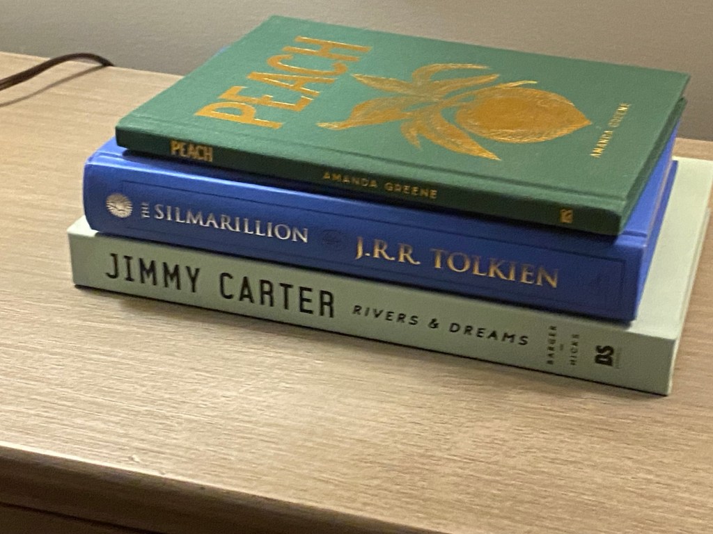 Stack of books including Amanda Green's "Peach," J.R.R. Tolkien's "The Silmarillion" and "Rivers and Dreams" by Jimmy Carter.