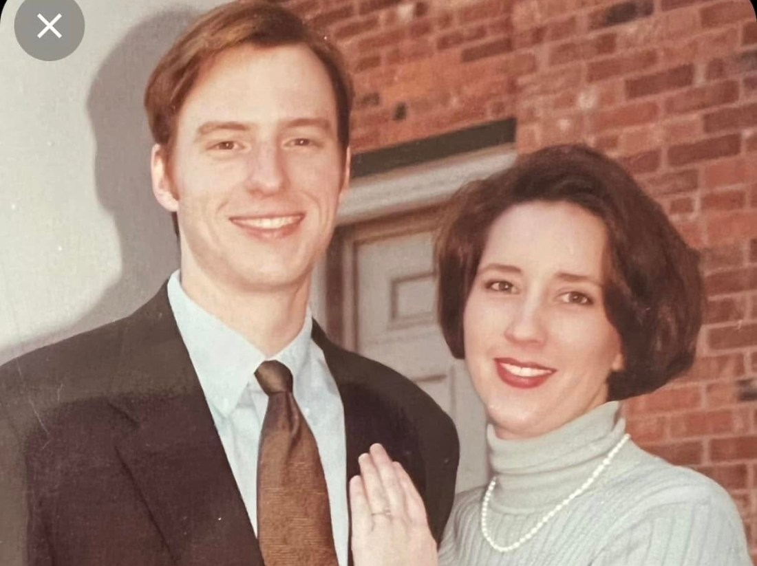 A young couple in front of a brick wall