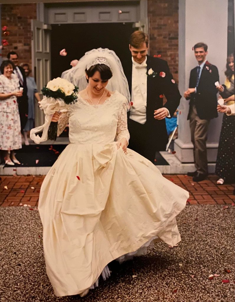 A couple leaves a church after their wedding in a flurry of rose petals