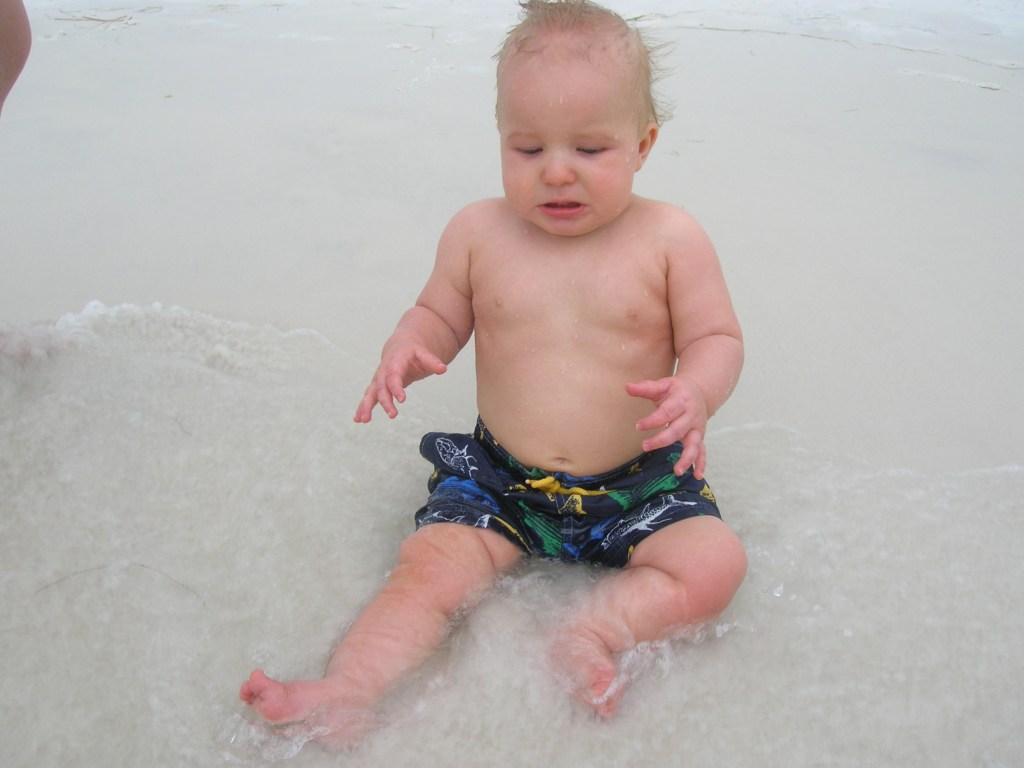 An infant at the water's edge at the beach