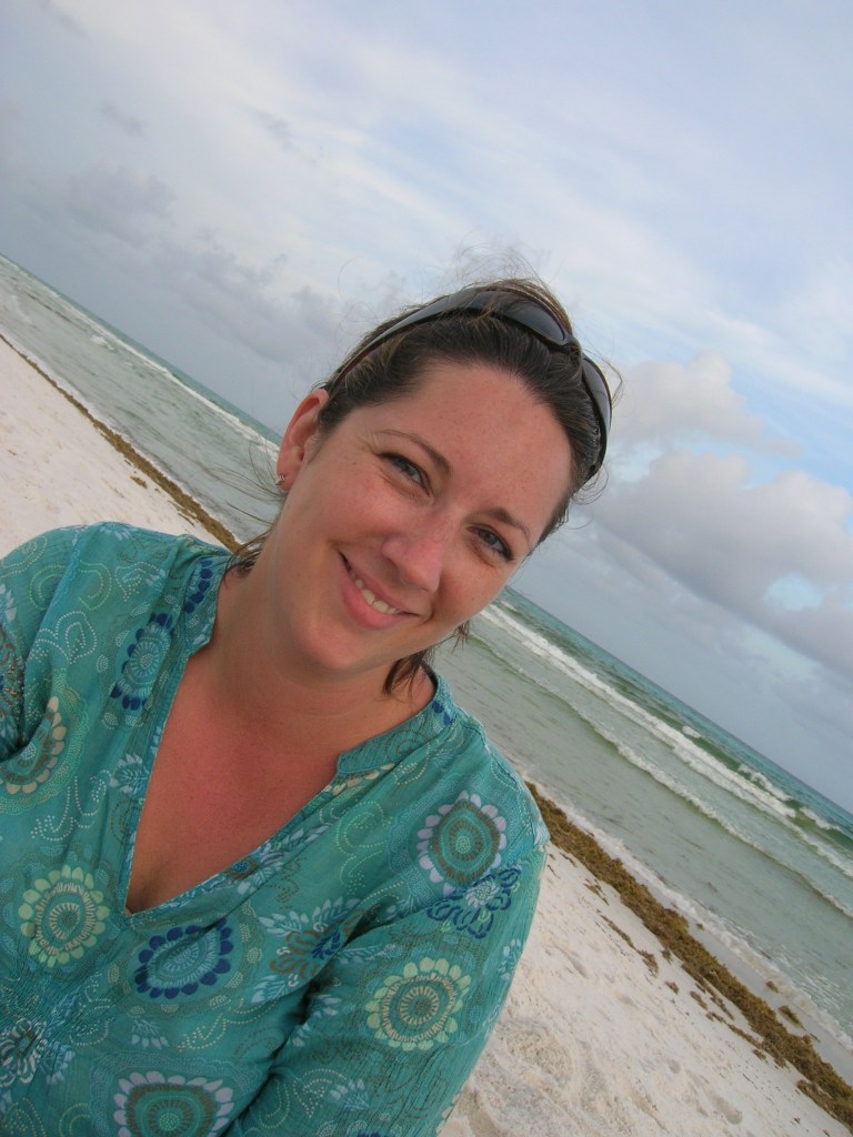 A woman at the beach in a turquoise shirt