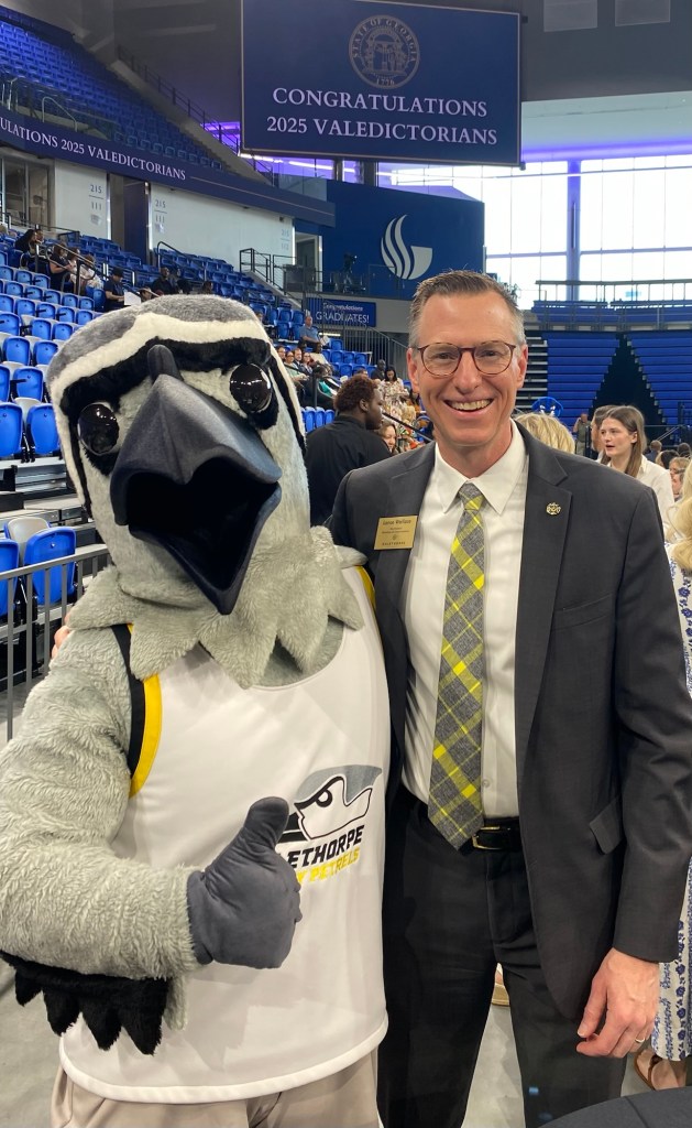 A man in a suit with a petrel mascot