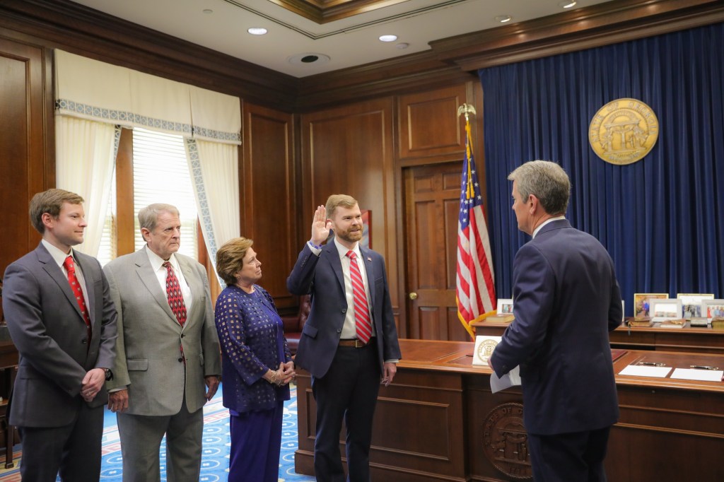 A man in suit with his family looking on taking an oath of office from the governor