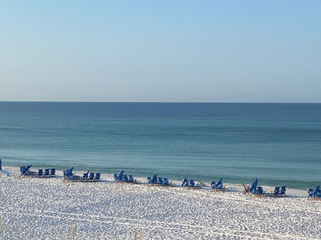 A white sand beach with blue umbrella and chair set ups at Santa Rosa Beach, Florida