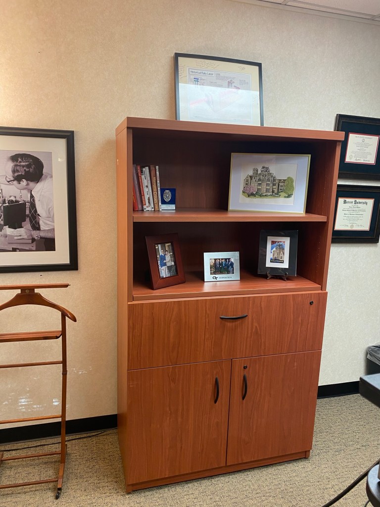 Book case with books and framed pictures on it in an office