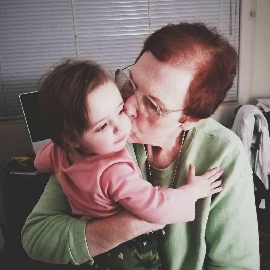 A grandmother kisses her infant granddaughter