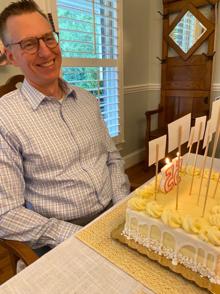 A man laughing with a birthday cake in front of him