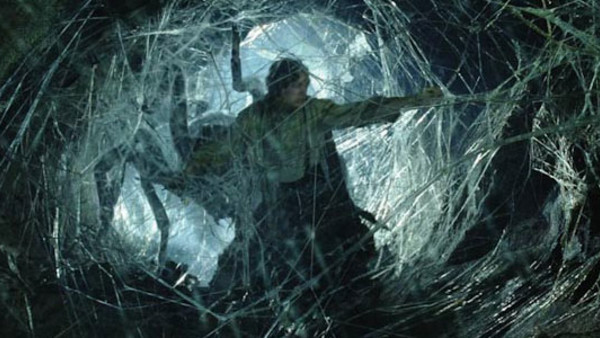 A hobbit ensnared in giant spider webs with a giant spider sneaking up behind him.