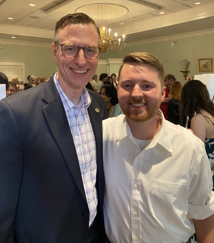 A man and his adult son in a crowded ballroom