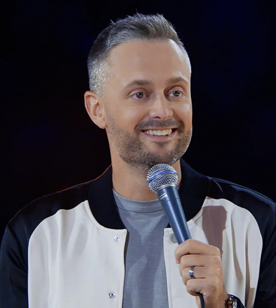 A man with gray hair and beard holding a microphone