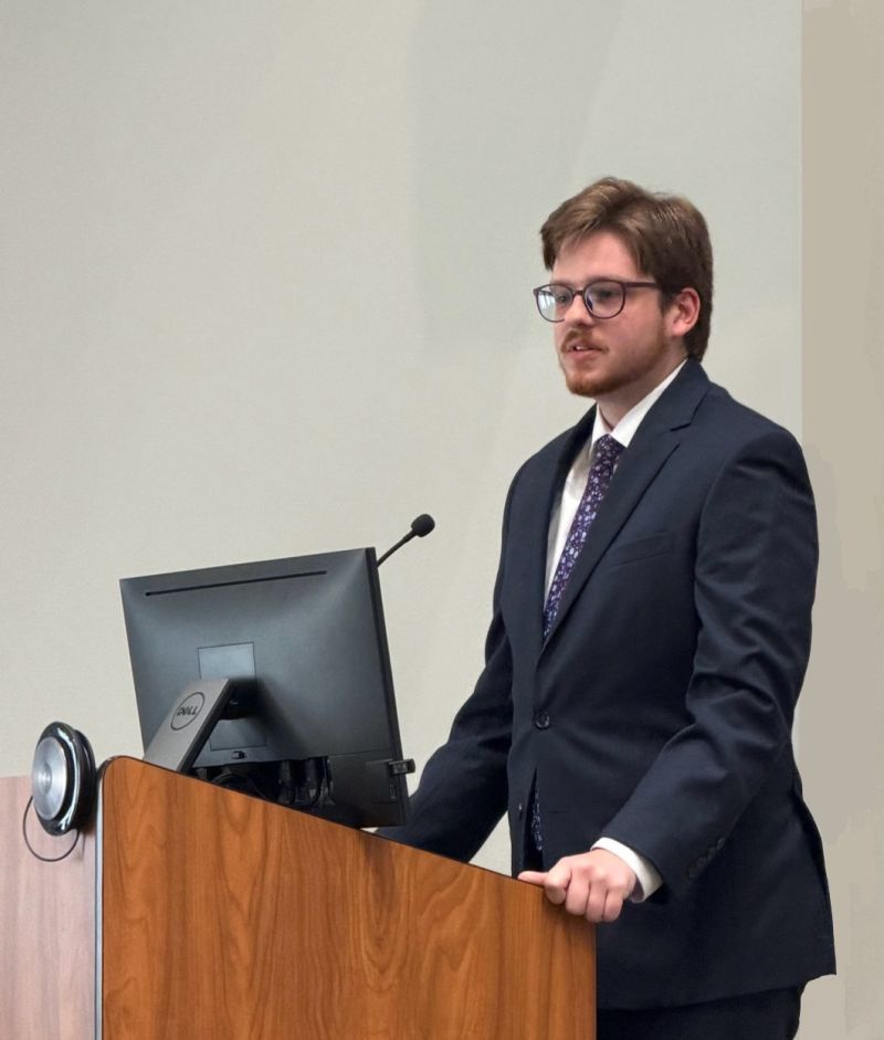 A young man in a suit and tie behind a podium