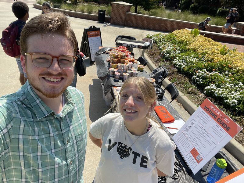 A young man and a young woman at a table promoting registering to vote