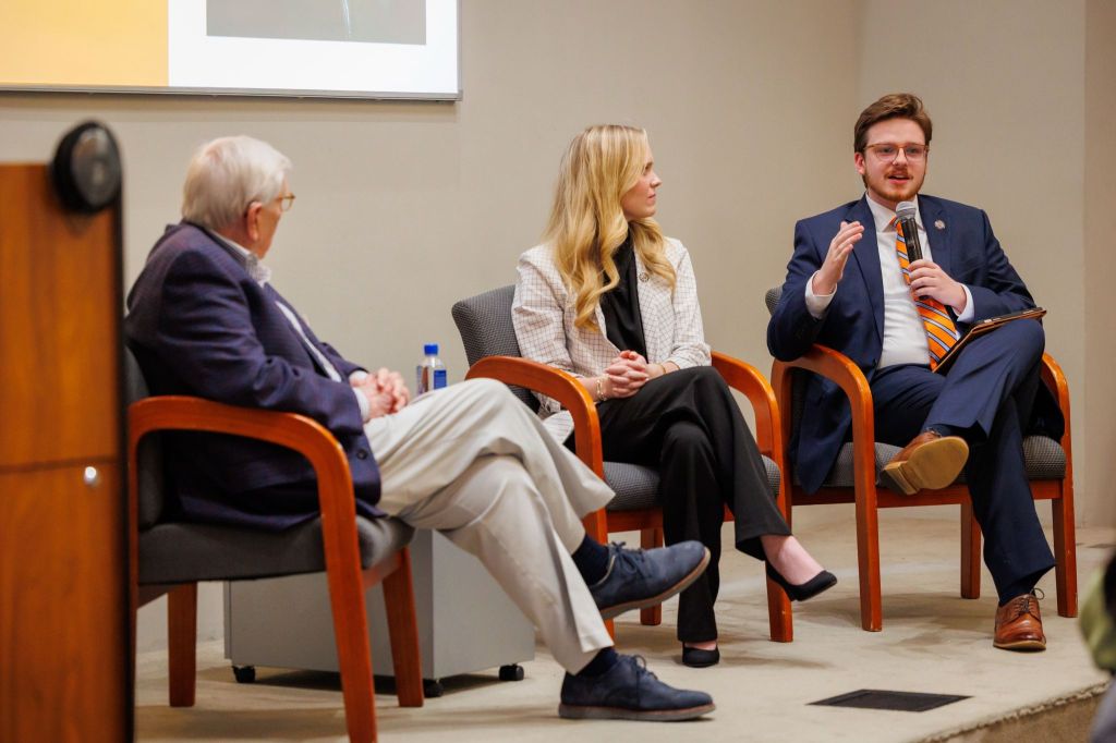Three people in chairs on a platform at a panel discussion