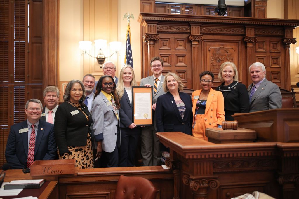 A delegation of Mercer University leaders with legislators on the floor of the Georgia House of Representatives