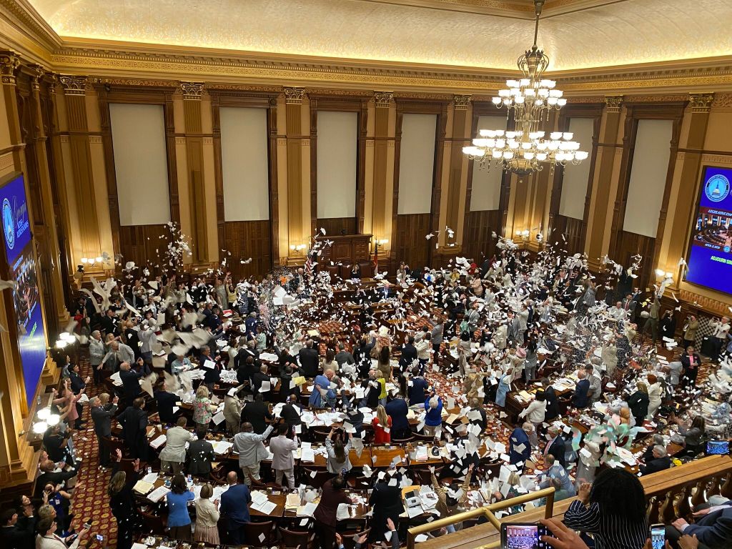 Representatives on the floor of the Georgia House throw shredded paper in the air